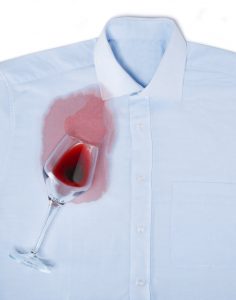 Glass of red wine spilled over a white shirt leaving a stain